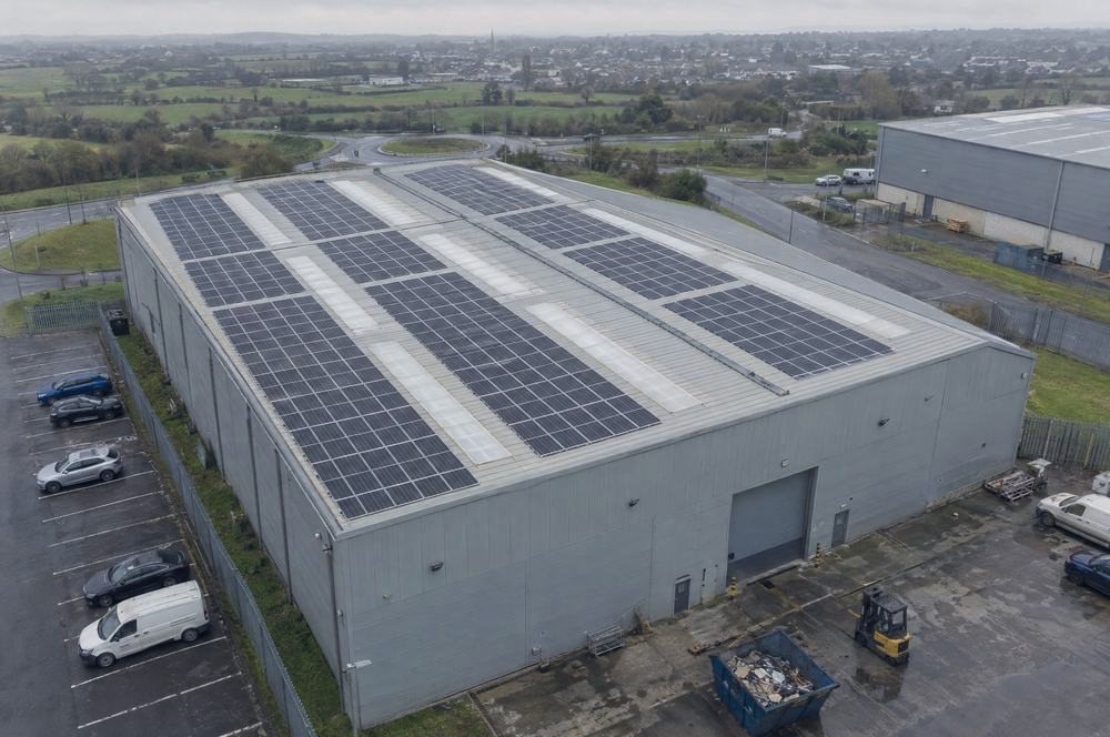 An aerial view of a warehouse roof covered in solar panels