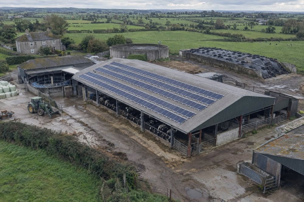 An aerial view of a farm shed with solar panels on the roof